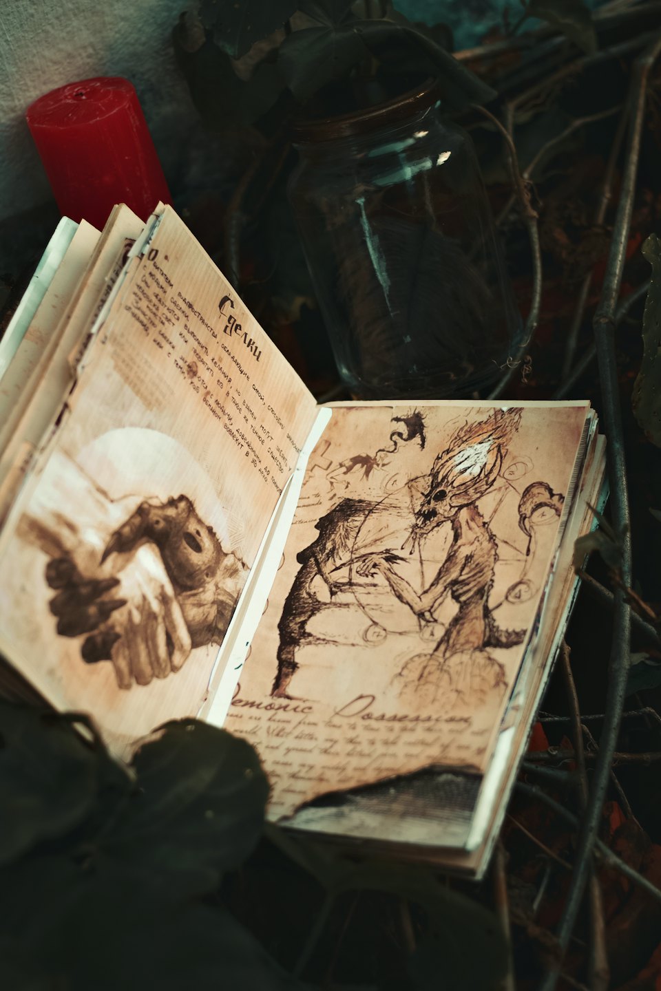 Ein aufgeschlagenes altes Buch mit Fabelwesen-Zeichnungen auf einer von Weinranken bedeckten Oberfläche.